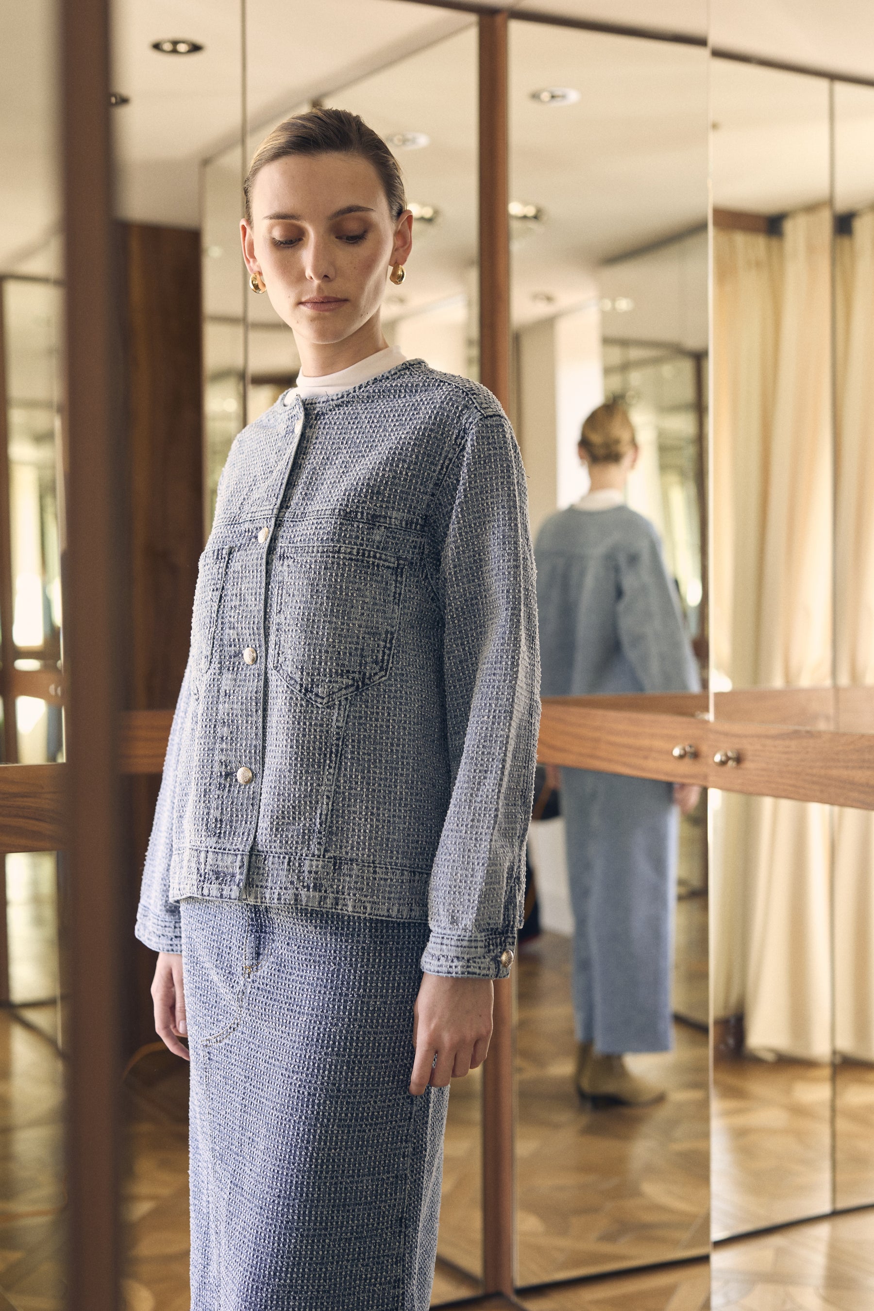 Person wearing a blue textured outfit standing in front of a mirror.