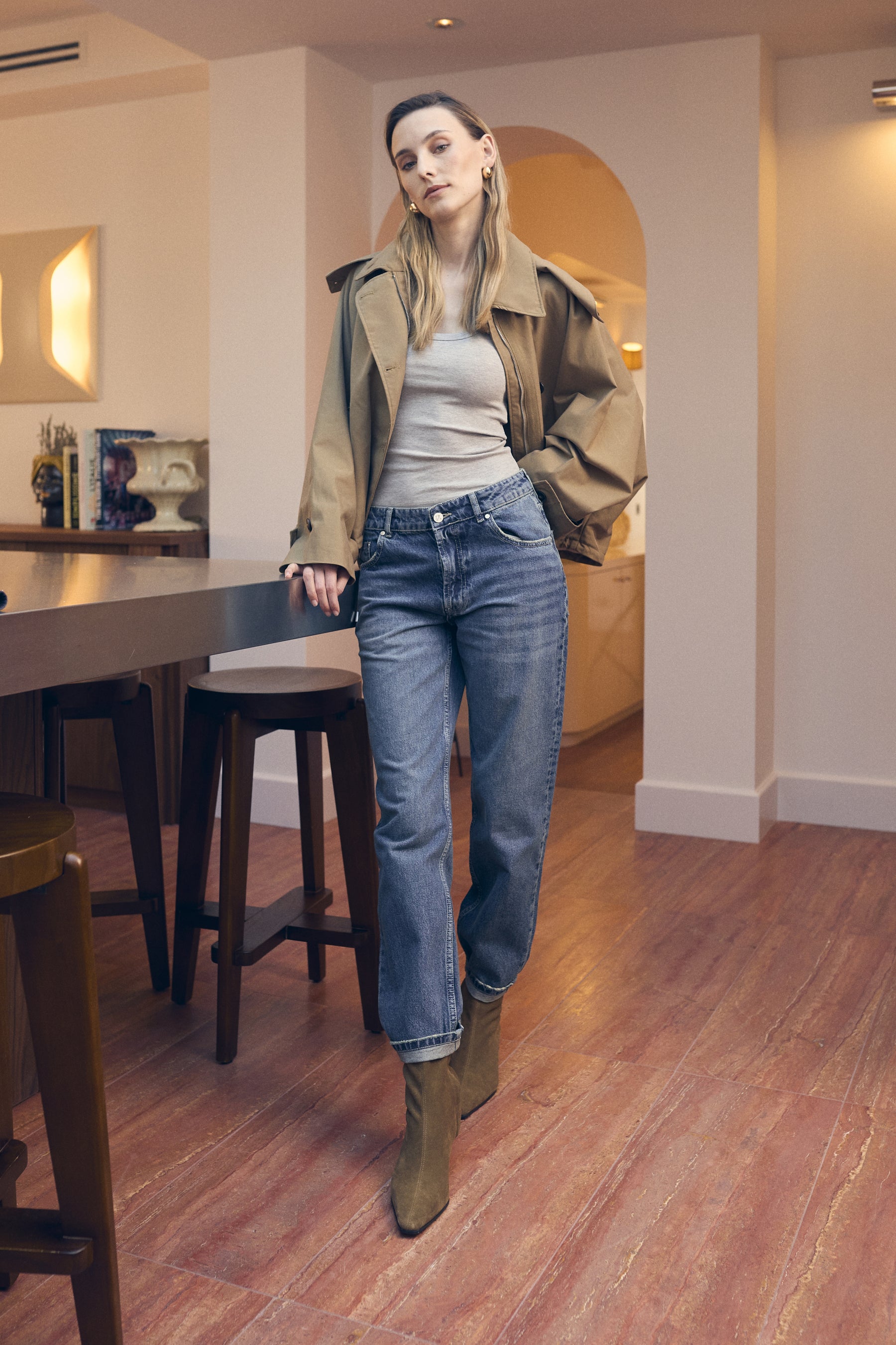 Woman in a casual outfit walking through a modern interior setting.